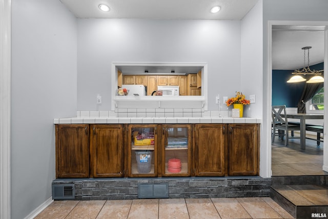 bar featuring fridge, white microwave, and visible vents