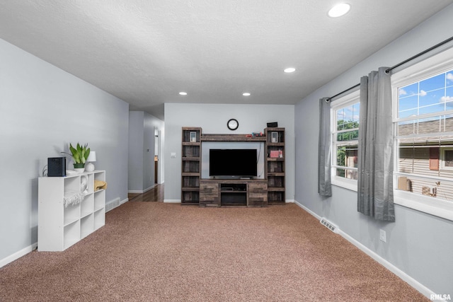 living area featuring a textured ceiling, carpet, visible vents, and baseboards