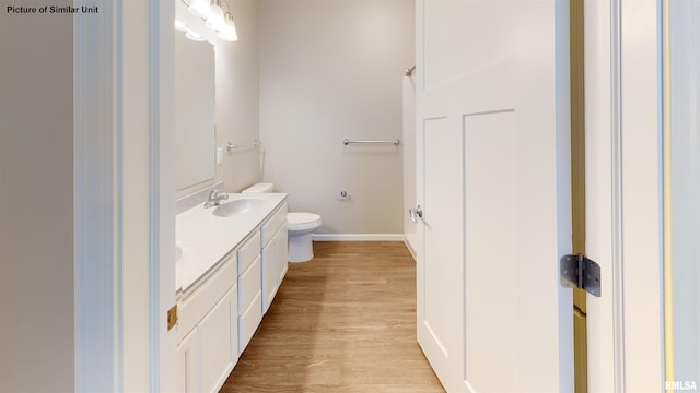 full bathroom featuring toilet, a sink, wood finished floors, double vanity, and baseboards