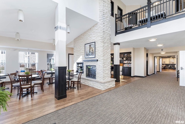 dining area with a fireplace, baseboards, a towering ceiling, and wood finished floors