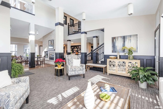 living area with a wainscoted wall, a high ceiling, stairs, and a decorative wall