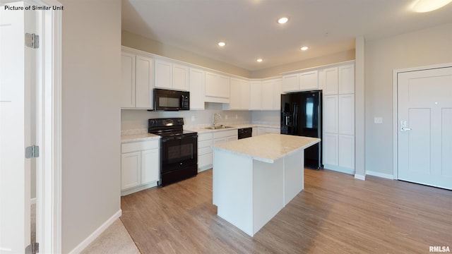 kitchen with a center island, light wood-style flooring, white cabinets, black appliances, and a sink