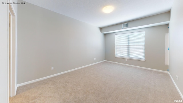 unfurnished room with visible vents, baseboards, and light colored carpet