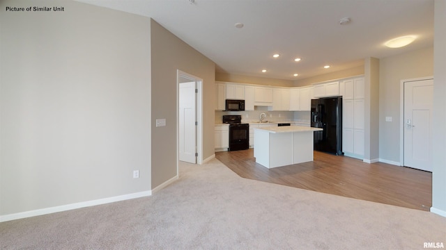 kitchen featuring light countertops, light carpet, white cabinets, black appliances, and a sink