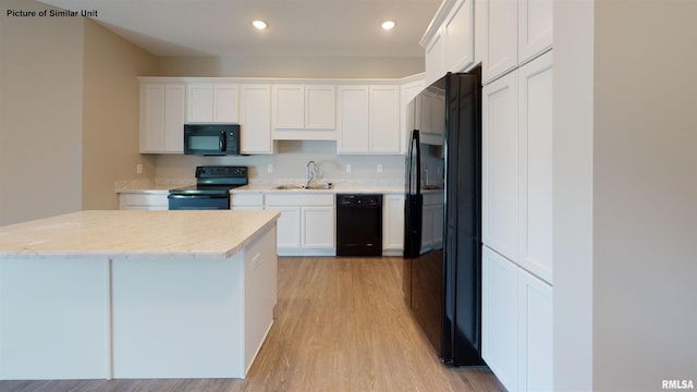 kitchen featuring white cabinetry, black appliances, light wood-style flooring, and a sink