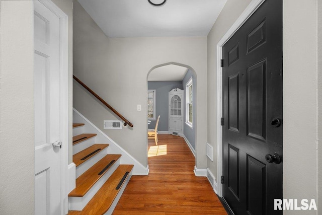 entrance foyer featuring visible vents, wood finished floors, stairway, arched walkways, and baseboards