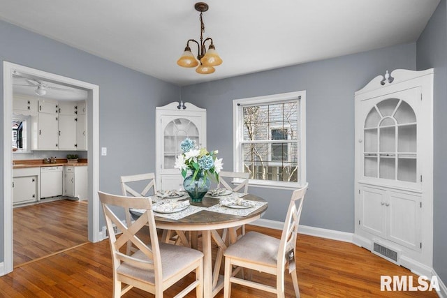 dining room featuring visible vents, baseboards, an inviting chandelier, and wood finished floors