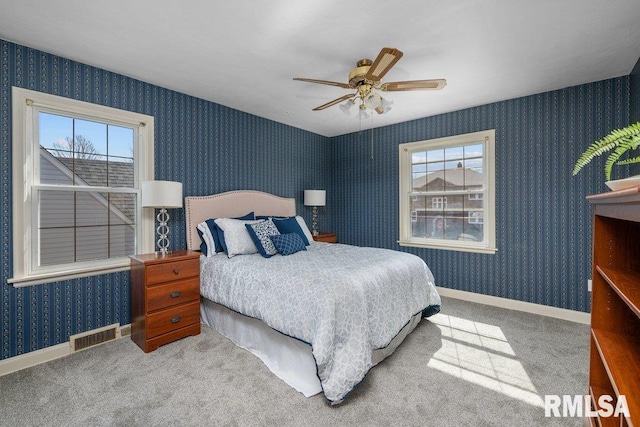 bedroom with visible vents, wallpapered walls, baseboards, carpet, and a ceiling fan