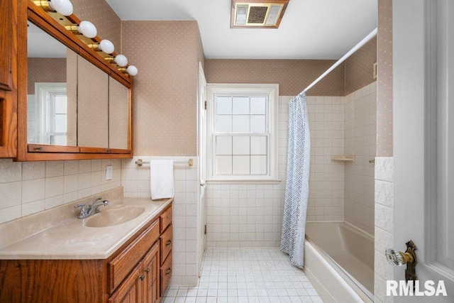 full bathroom with visible vents, wallpapered walls, tile walls, shower / tub combo with curtain, and vanity