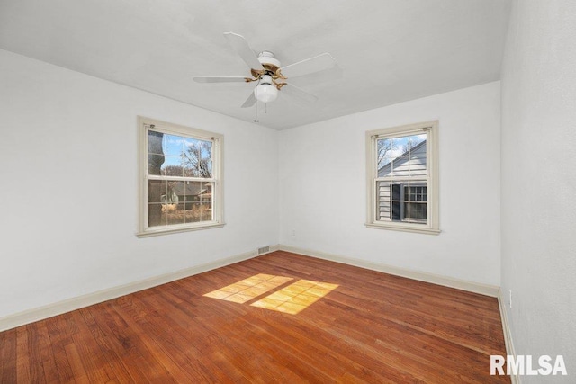 spare room featuring visible vents, baseboards, wood finished floors, and a ceiling fan