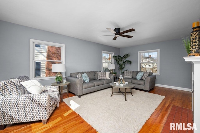 living room featuring a fireplace, baseboards, ceiling fan, and wood finished floors