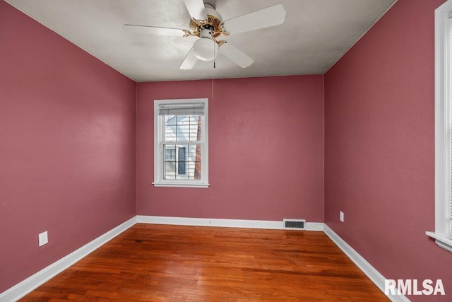 empty room featuring visible vents, a ceiling fan, baseboards, and wood finished floors