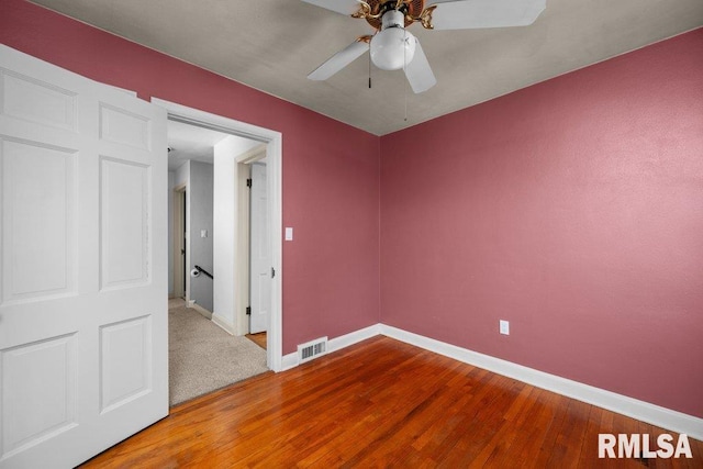 unfurnished room with ceiling fan, visible vents, baseboards, and wood finished floors