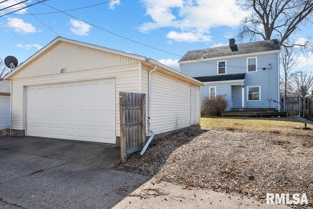 view of front facade with a chimney, a detached garage, an outdoor structure, and fence