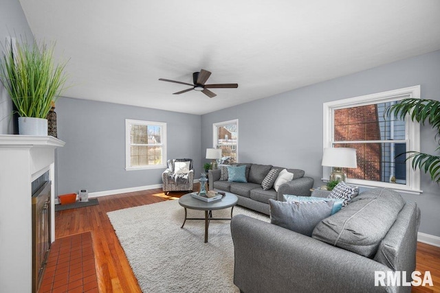 living area with wood finished floors, baseboards, and a tile fireplace