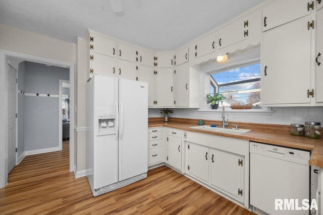 kitchen with a sink, light wood-type flooring, white appliances, and white cabinets