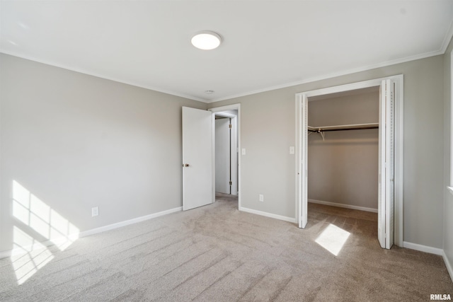 unfurnished bedroom featuring baseboards, a spacious closet, a closet, crown molding, and carpet flooring