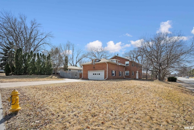 exterior space featuring an attached garage, fence, brick siding, and driveway