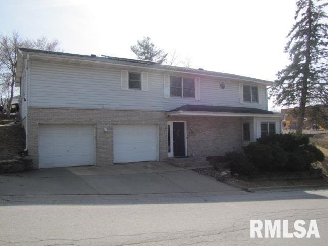 traditional home featuring an attached garage, brick siding, and driveway