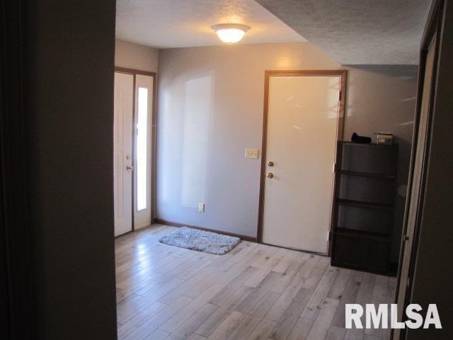 foyer featuring light wood-type flooring and a textured ceiling