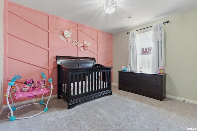 carpeted bedroom featuring visible vents, a decorative wall, and baseboards