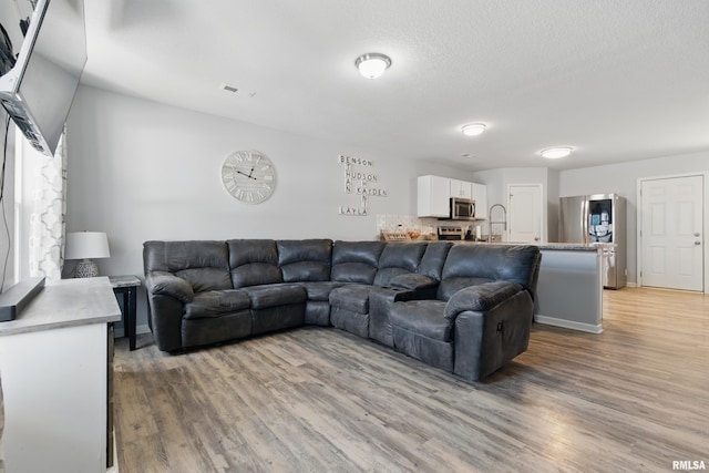 living room featuring visible vents, a textured ceiling, and light wood-style flooring