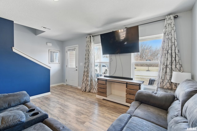 living room with visible vents, a textured ceiling, baseboards, and wood finished floors