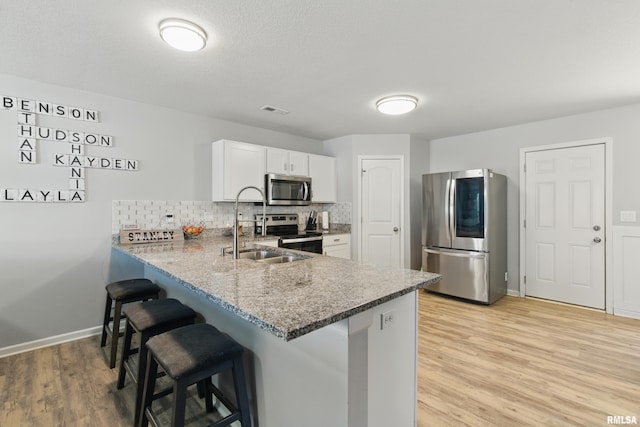 kitchen with visible vents, a kitchen breakfast bar, tasteful backsplash, appliances with stainless steel finishes, and a peninsula