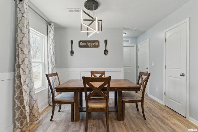 dining room with visible vents, wainscoting, and wood finished floors