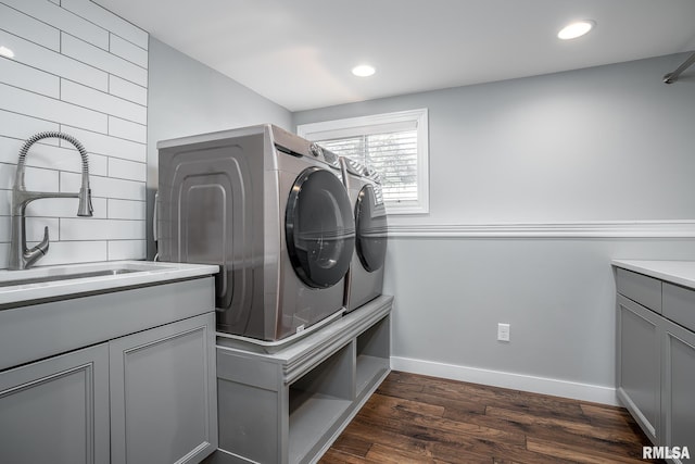 clothes washing area featuring baseboards, washing machine and clothes dryer, cabinet space, a sink, and dark wood-type flooring