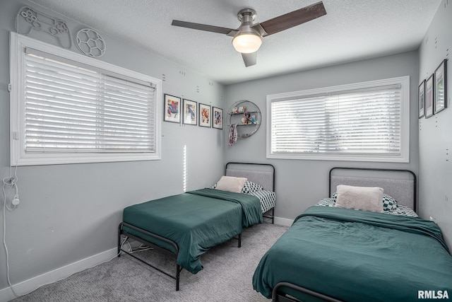 carpeted bedroom featuring a textured ceiling, baseboards, and a ceiling fan