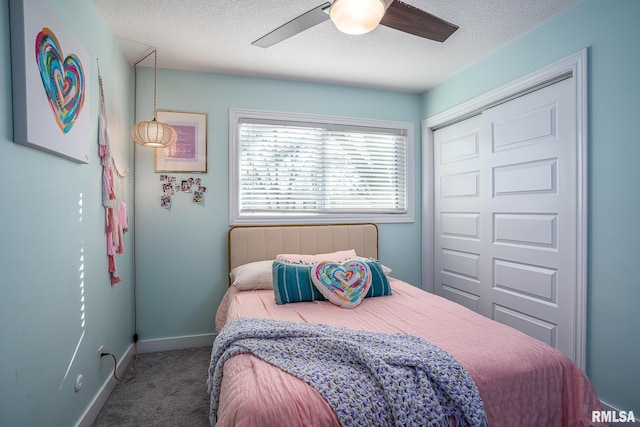 bedroom with baseboards, ceiling fan, a closet, a textured ceiling, and carpet flooring