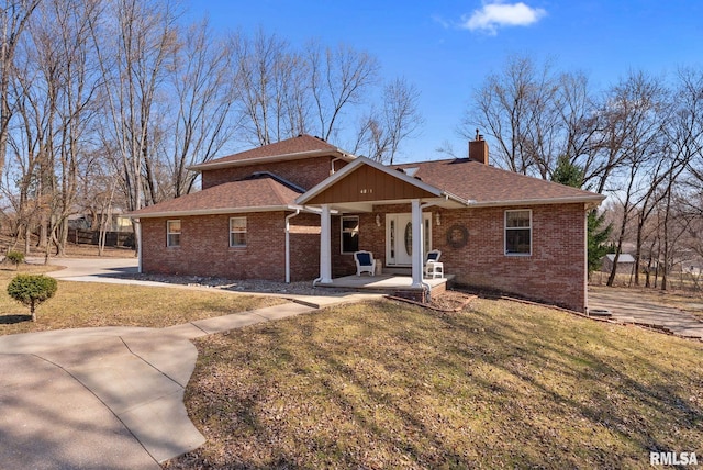 view of front of property featuring a front yard, brick siding, roof with shingles, and a chimney