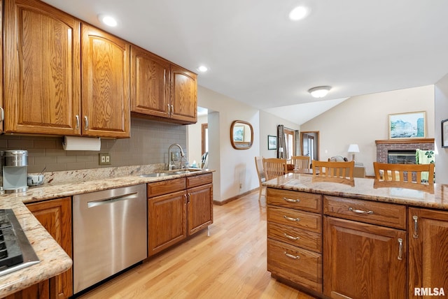 kitchen featuring a sink, a brick fireplace, brown cabinetry, and stainless steel appliances