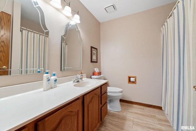 full bath with vanity, toilet, baseboards, and visible vents