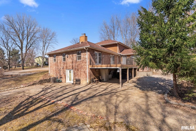 back of house featuring a wooden deck, brick siding, and a chimney