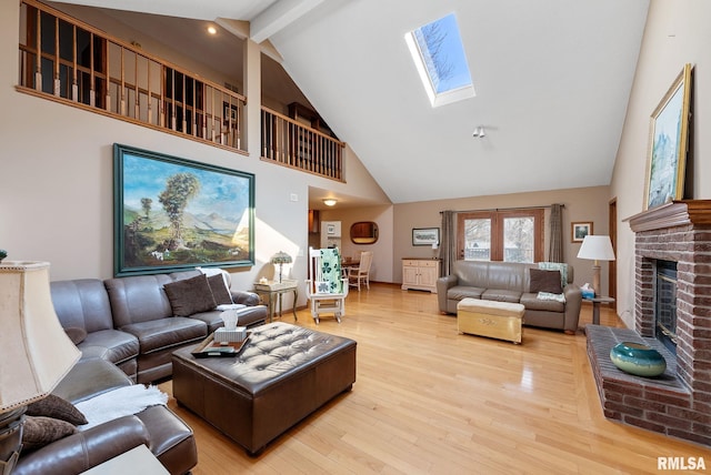 living room featuring beam ceiling, high vaulted ceiling, wood finished floors, a skylight, and a fireplace