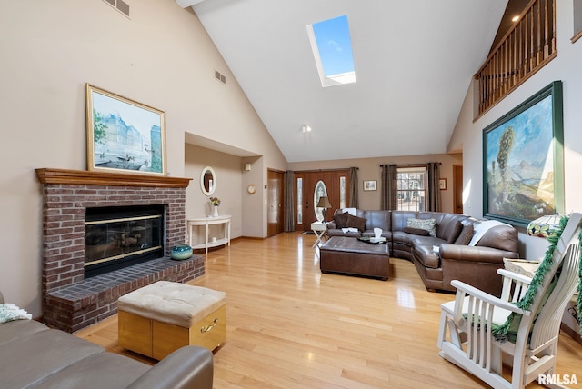 living room featuring visible vents, a fireplace, a skylight, and wood finished floors