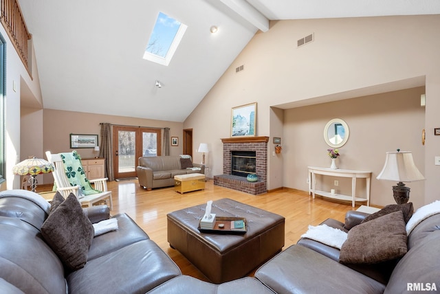 living area with beam ceiling, a skylight, light wood-style floors, and visible vents