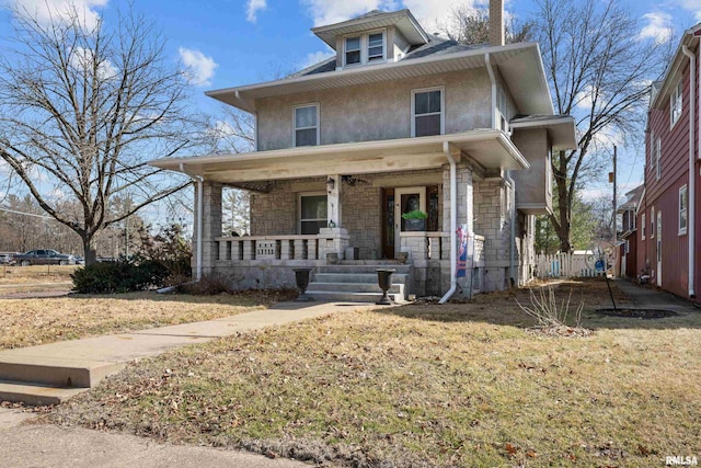 traditional style home with a front yard, covered porch, and stone siding