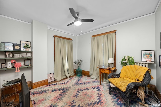 living area with baseboards, ceiling fan, and crown molding