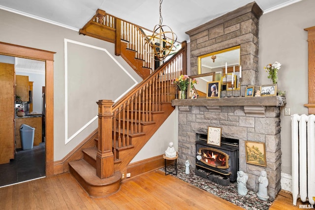 stairway featuring radiator, baseboards, ornamental molding, an inviting chandelier, and wood-type flooring