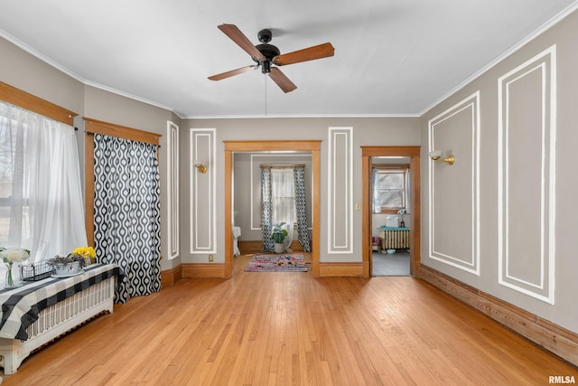 interior space featuring crown molding, radiator heating unit, light wood-style floors, and a healthy amount of sunlight