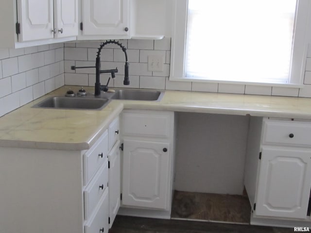 kitchen featuring white cabinetry, decorative backsplash, light countertops, and a sink