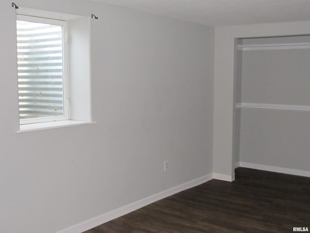 empty room featuring baseboards and dark wood finished floors