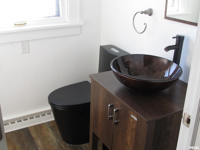 bathroom with a baseboard heating unit, toilet, wood finished floors, and vanity