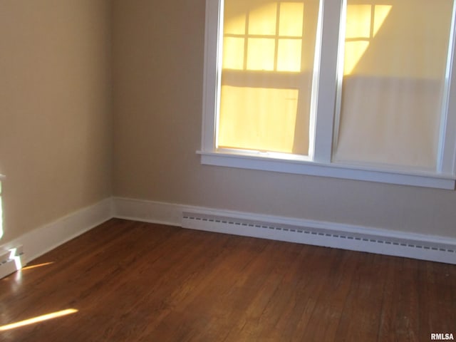 spare room with baseboards, baseboard heating, and wood finished floors