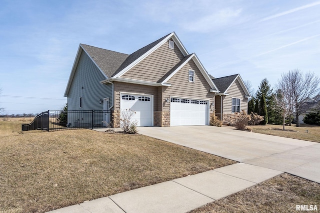 view of home's exterior featuring stone siding, driveway, a yard, and fence