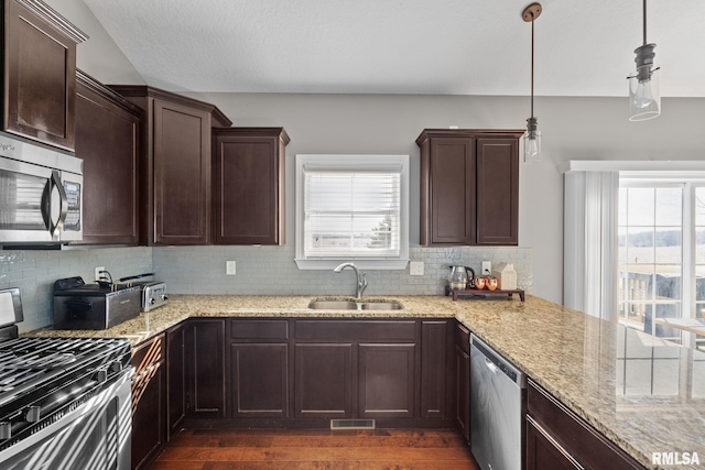 kitchen with dark wood-style flooring, light stone countertops, stainless steel appliances, and a sink