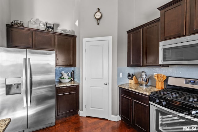 kitchen with light stone counters, stainless steel appliances, dark brown cabinets, and dark wood-style flooring